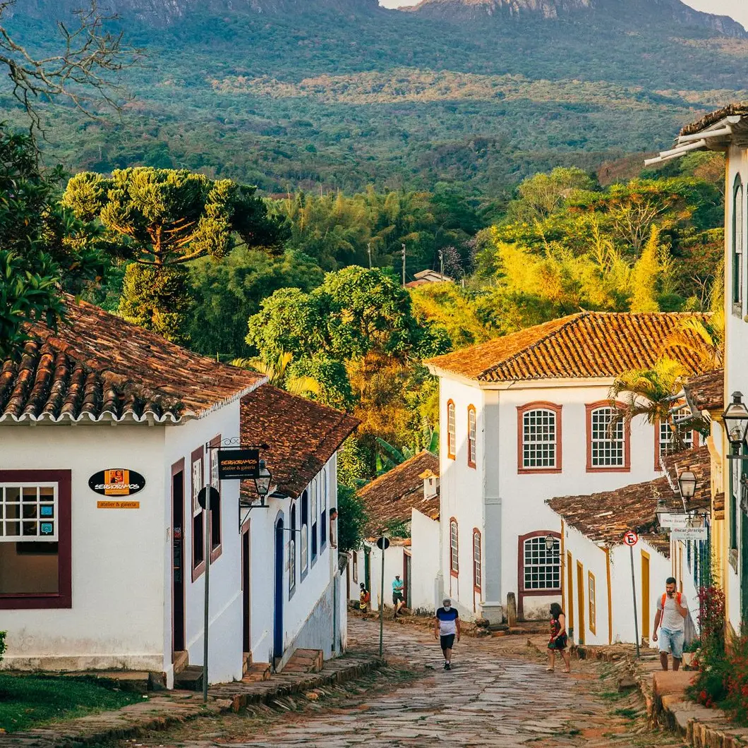 a cobblestone street with white buildings and mountains in the background